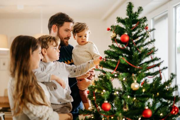 istock Mother and father decorating christmas tree with their kids 1279128112