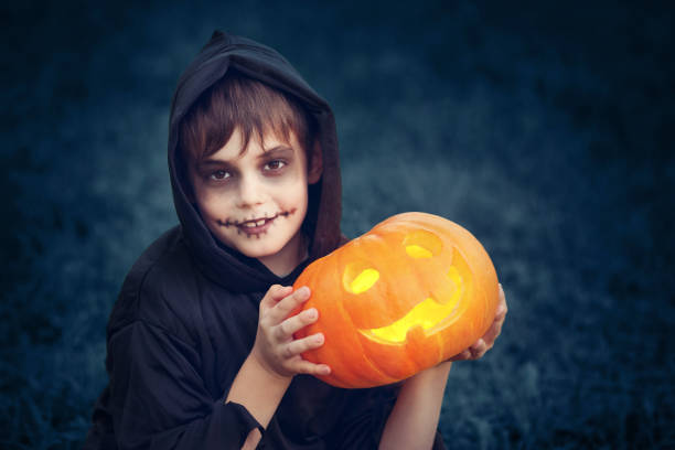 istock Child in scary costume with pumpkin 1279131683