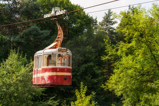 Old abandoned red rusty cable car hanging on a rope as an example of Soviet culture