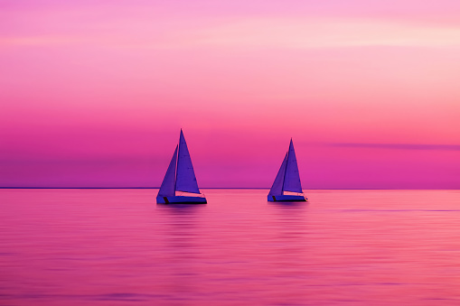 Sailing boat yachts in the sunlight. Sailboats at the sunset. Luxury vacation. Summer adventures. Blurred sea water. Maritime competitions. Regatta race