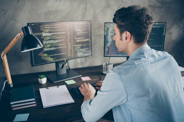 istock Rear back behind view portrait of his he nice attractive focused geek guy typing css analyzing cyberspace security building at modern industrial interior style concrete wall work place station 1279133450
