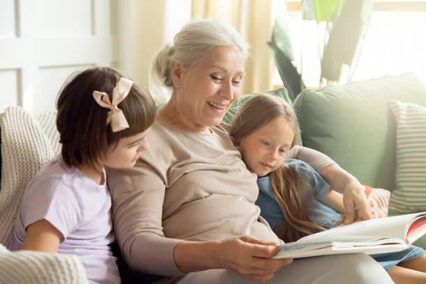 istock Grandmother reading a book to two granddaughters 1279137356