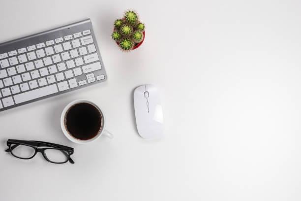 istock Workspace with computer keyboard, office supplies, and coffee cup on white background. Top view with copy space. 1279138464