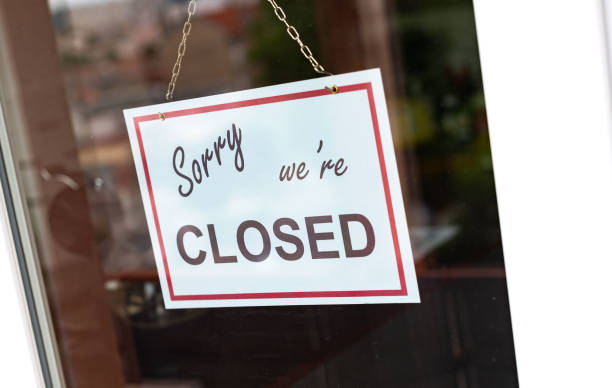 istock Closed sign hanging behind a store window 1279139804