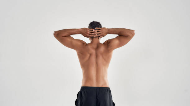 back view of muscular man with naked torso keeping arms over the head isolated over grey background, posing in studio - rear view human arm naked men imagens e fotografias de stock