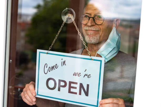 istock Store owner hanging open sign on window 1279140190