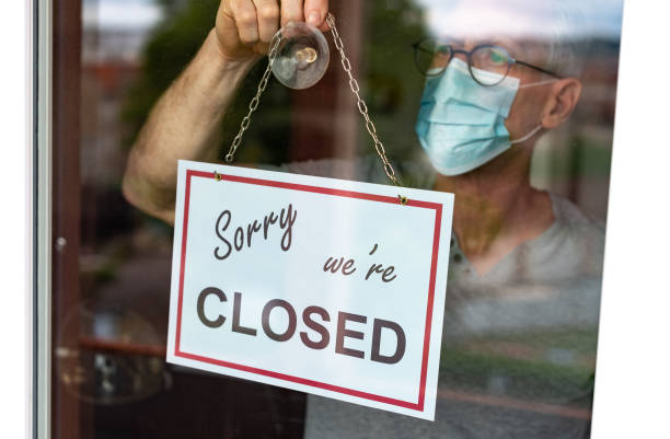 istock Store owner hanging closed sign on window 1279140202