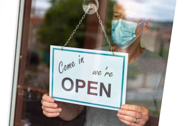 istock Store owner hanging open sign on window 1279140214