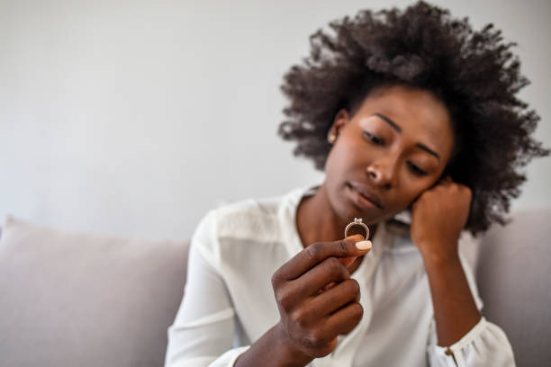 jeune femme déprimée bouleversée retenant l’anneau de mariage à l’intérieur - violence black men women photos et images de collection