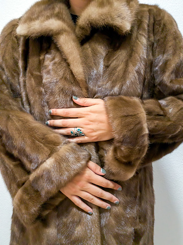 Unrecognizable stylish woman in rich fur coat. Woman's hand with painted nails.