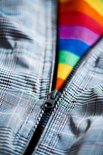 gay pride flag coming out from a jacket closeup of an unzipped casual gray jacket letting see a gay pride flag inside rainbow flag photos stock pictures, royalty-free photos & images