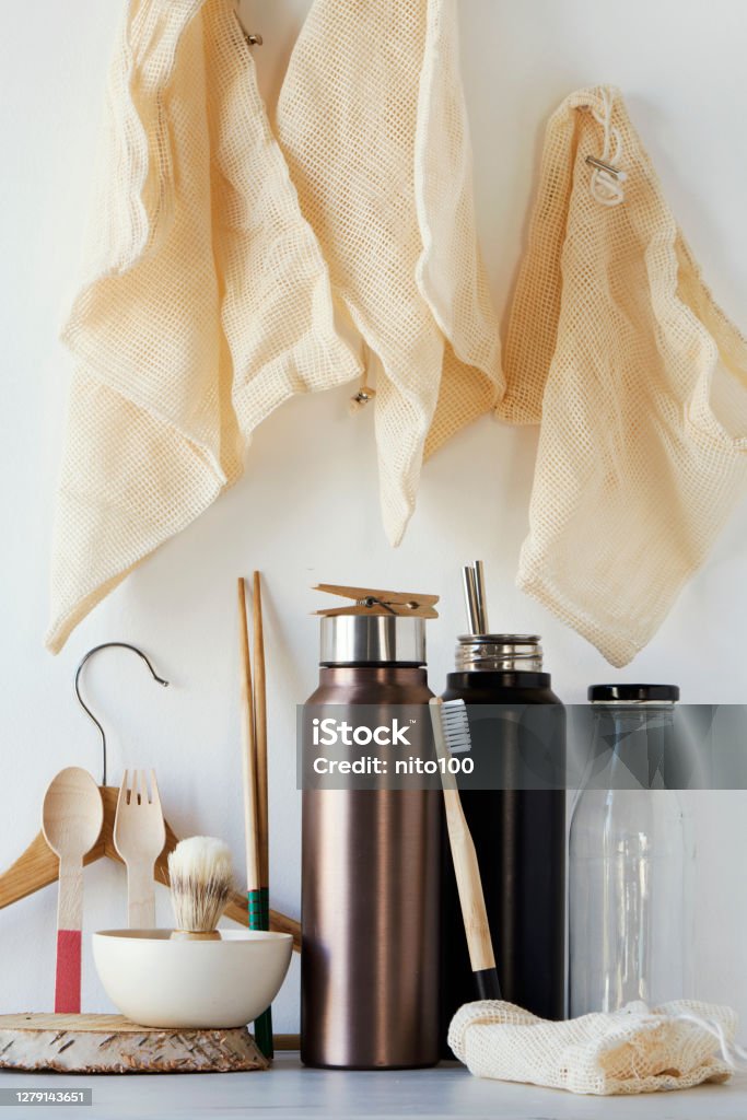 no-plastic sustainable household items a pile of no-plastic sustainable household items, such as refillable water bottles, a glass bottle, shopping mesh bags, a wooden shaving brush and toothbrush, or reusable wooden cutlery and chopsticks Alternative Lifestyle Stock Photo