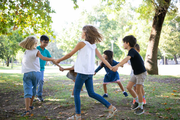 istock Group of children holding hands and dancing around 1279143771