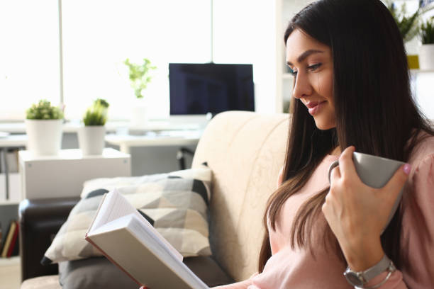 istock Beautiful young woman reading book at home 1279144784