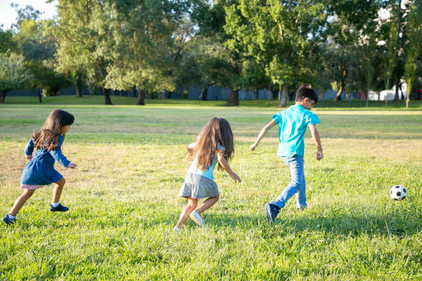 istock Group of active kids playing football on grass 1279146652
