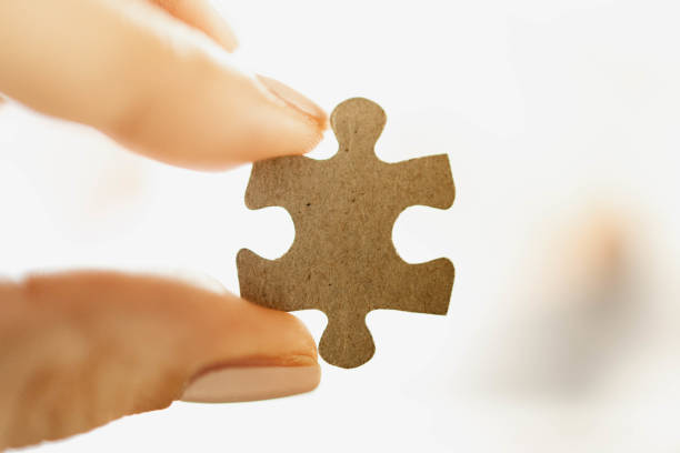 istock Two hands holding and putting a piece of white jigsaw puzzle 1279148078