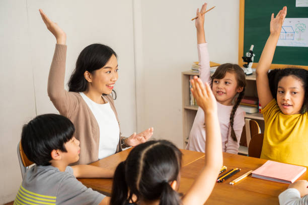 istock Asian school teacher with students raising hands 1279151451