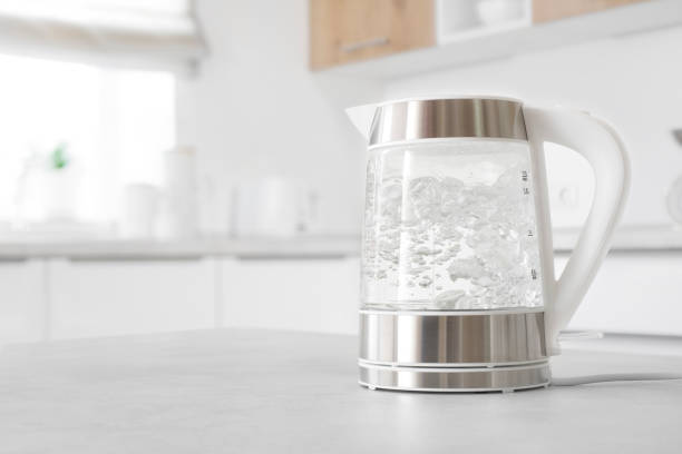Modern glass electric kettle boiling on kitchen table