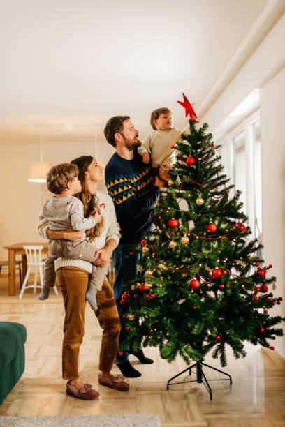 familie schmückt weihnachtsbaum - weihnachten familie stock-fotos und bilder