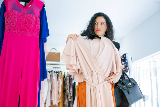 istock Serious female shopper holding hanger with cloth 1279162084