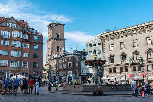 Copenhagen, Denmark - August 27, 2019: The Caritas Well (Caritasbrønden), or the Caritas Fountain (Caritasspringvandet), is the oldest fountain in Copenhagen, located on Gammeltorv, part of the Strøget zone, with people around in Copenhagen, Denmark