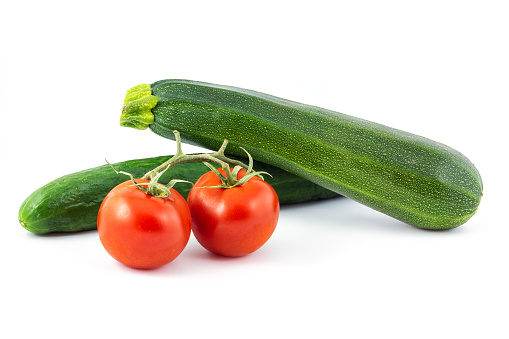 Green cucumber, green zucchini and two red tomatos isolated on a white background. Healthy food.