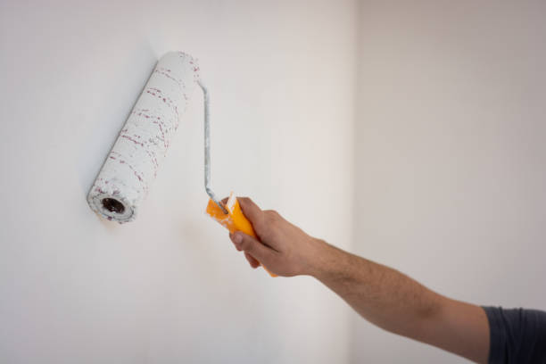 istock Men holding a paint roller soaking in white wall paint 1279165547