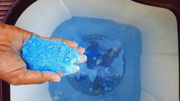 istock Blue detergent powder in hands and adding it in water in washing machine 1279166115