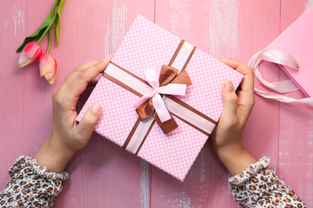 istock women hand holding pink color gift box, top view 1279166212