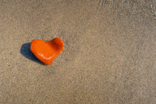 orange heart shaped stone at the beach