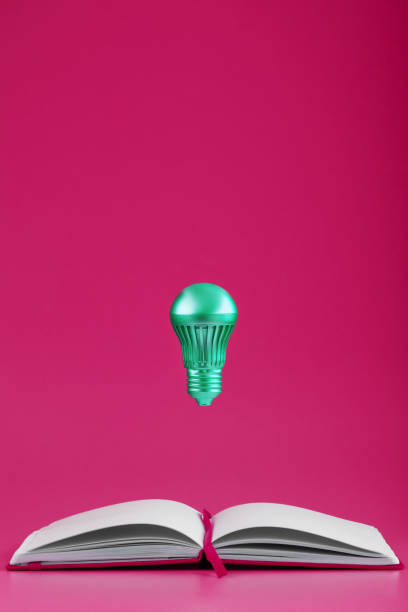 istock The light bulb hovers over the open pages of an empty notebook on a pink background. 1279166370