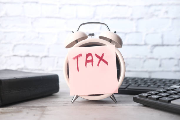istock Tax word on alarm clock with stationary on table. 1279166928