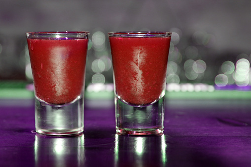 Close-up of two red cocktail shots on bar counter on blurred background