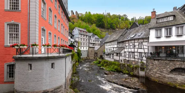 Bright and colorful autumn day with traditional houses along the Rur river in the city center of Monschau, a beautiful resort town in the Eifel region of Germany.