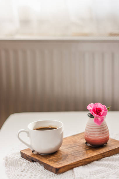 istock Cup of coffee and flower in vase on white table 1279180166