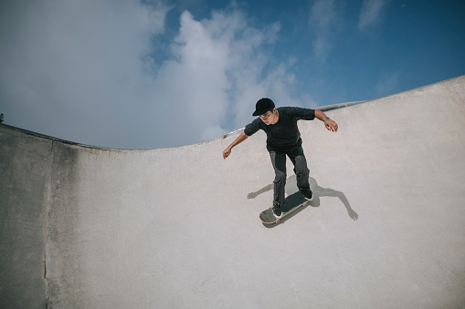 Asian male skateboarder in action at skateboard park