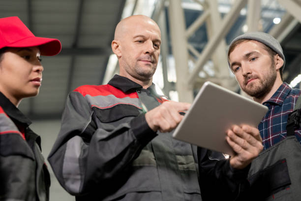 istock Serious bald mature foreman with tablet making presentation to subordinates 1279180390