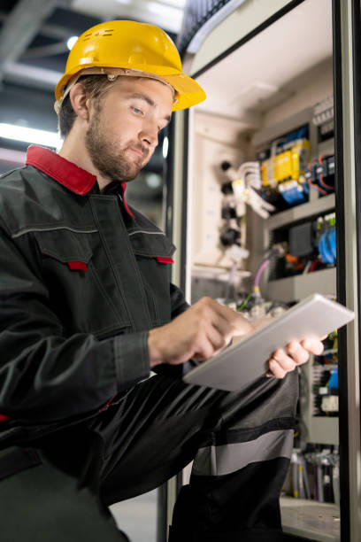 istock Young bearded engineer in workwear and hardhat checking settings of machine 1279180457