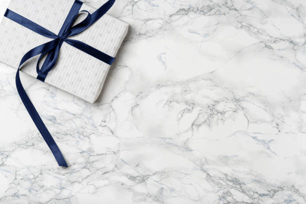 istock Christmas white gift with blue ribbon on marble background 1279181414