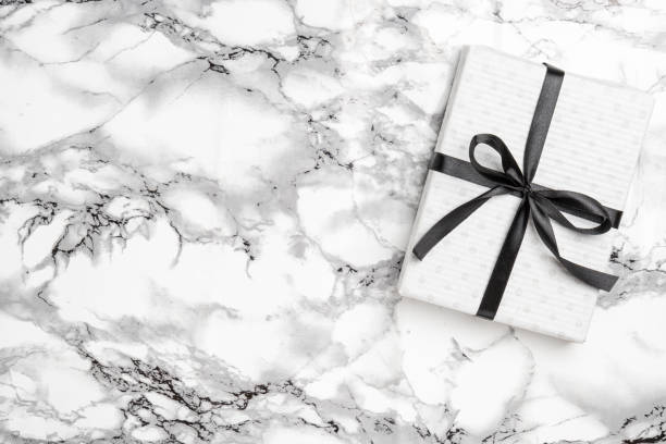 istock Christmas white gift with black ribbon on marble background 1279181455