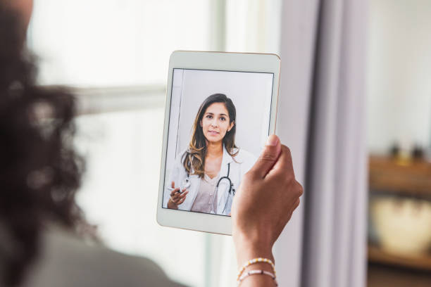 Unrecognizable woman talks with doctor during telemedicine visit A female doctor offers an unrecognizable female patient advice during a telemedicine appointment. over the shoulder view photos stock pictures, royalty-free photos & images