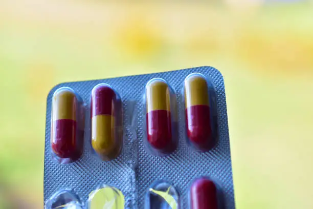Package of red and yellow pills in the afternoon on the background of the window