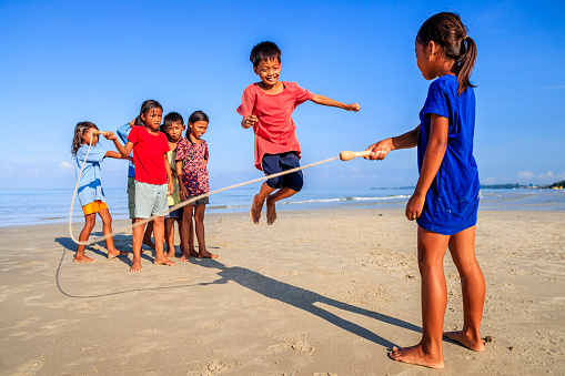 Group of Cambodian children having fun with jumping rope on the beach, Cambodia