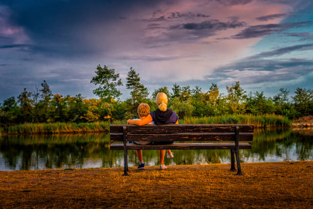 istock mother and child watching a sunset over a quiet lake 1279198566