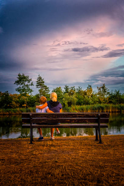 istock mother and child watching a sunset over a quiet lake 1279198665