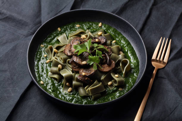 Spirulina pasta with mushrooms, spinach sauce and pine nuts