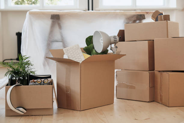 istock Abundance of moving boxes stacking on floor against table covered with polyethylene in new office 1279200977