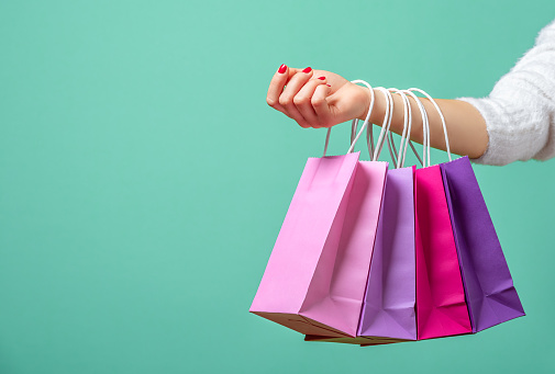 Bolsas de compras en la mano de las mujeres. Mujer comprando con bolsas de papel de colores. photo