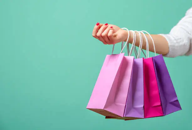 Photo of Shopping bags on womans hand. Woman shopping with colored paper bags.
