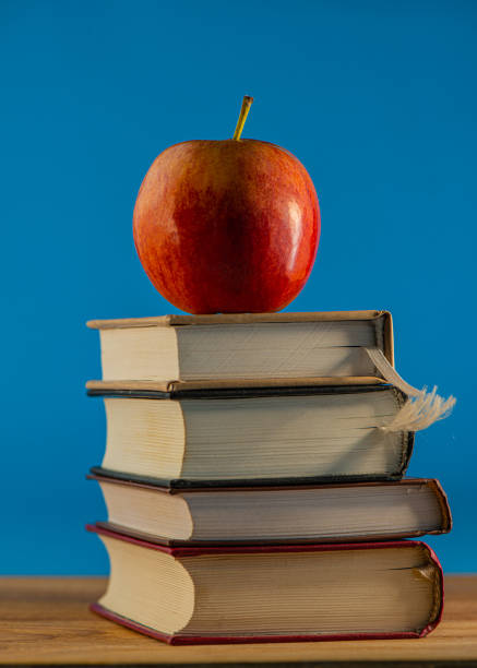 istock Red apple on a stack of books lying on the surface of an oak table. 1279205853